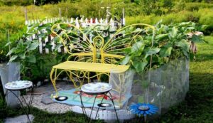 Sunflowers are planted in a U-shape to create the walls of a sunflower house with a yellow bench shaped like a butterfly inside.